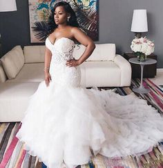 a woman in a white wedding dress standing on a colorful carpeted living room floor