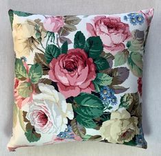 a pink and green floral pillow sitting on top of a bed