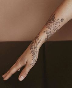 a woman's arm with flowers on it and a hand that is holding the wrist