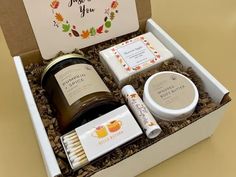 an open gift box containing the contents of a candle, soap, and lotion