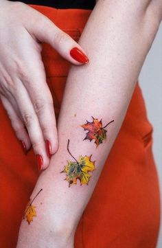 a woman's arm with autumn leaves on it