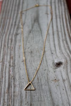 "A beautiful, shiny gold triangle strung from a gold plated or 14k gold filled chain. This simple, everyday minimalist necklace is the perfect piece to wear alone or layered with other necklaces. It makes the perfect gift for yourself or any loved one. You'll surely love the dainty design of the simple triangle necklace. D E T A I L S: Triangle - Gold Plated Brass - Approximately 1/2\" wide - Beautiful & shiny Chain - Gold plated brass or 14k gold filled - Any length up to 18\" - Delicate, b Elegant Triangle Everyday Jewelry, Minimalist Geometric Necklaces For Everyday, Minimalist Geometric 14k Gold Jewelry, Minimalist 14k Gold Geometric Jewelry, Minimalist Geometric Jewelry In 14k Gold, Minimalist Triangle Jewelry For Gifts, Minimalist Triangle-shaped Jewelry For Gifts, Minimalist Gold Charm Necklace, Minimalist Triangle Gold Jewelry