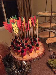 there is a cake with fruit on it and flags in the shape of arrows sitting on a plate