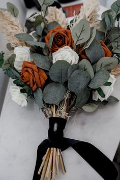 a bouquet of flowers sitting on top of a white table next to a black ribbon