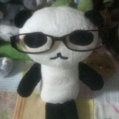 a stuffed panda bear wearing glasses on top of a bed