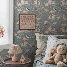 a teddy bear sitting on top of a bed next to a table with a lamp