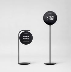 two black and white signs on poles with the words open, no time written on them