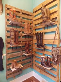 several pairs of cowboy boots are displayed on wooden shelves in a room with blue walls