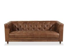 a brown leather couch sitting on top of a white floor