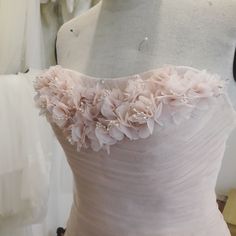 a white dress with flowers on it sitting on a mannequin