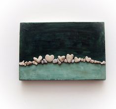 a green box with rocks in the shape of hearts on it's side, against a white background