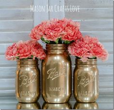 three gold mason jars with pink flowers in them