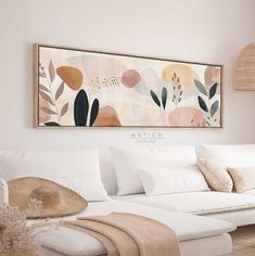 a living room with white couches and art on the wall above it, along with pillows