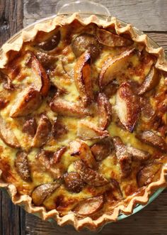 a pie sitting on top of a wooden table next to a glass bowl filled with food