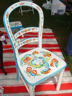 a painted chair sitting on top of a red and white striped rug in the grass