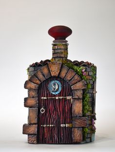 a miniature house made out of wood and stone with a door that has an evil eye on it