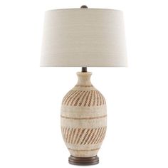 a table lamp with a white and brown striped vase on it's base, next to a beige linen shade