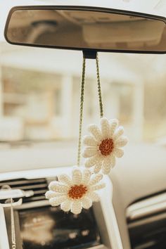 two crocheted flowers hanging from the dashboard of a car