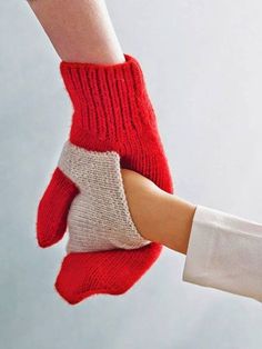 two hands holding each other wearing red and white knitted mittens, with facebook page below