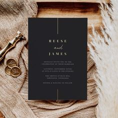 a black and gold wedding card with the words reese and james on it next to a pair of scissors