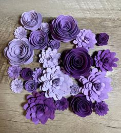 purple paper flowers are arranged on a wooden surface