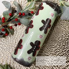 a green cup with red and black designs on it sitting on a table next to berries