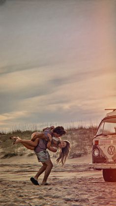 two people are playing in the sand near a vw van and an old car