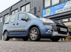 a small blue car parked in front of a building