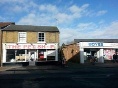 the pet shop is on the side of the road with people walking in front of it