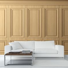 a white couch sitting next to a table on top of a hard wood floor in front of wooden paneled walls