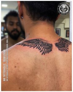 the back of a man's neck with black wings on it