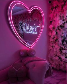 a pink room with a heart shaped neon sign on the wall next to a chair