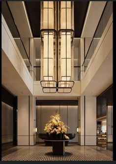 an elegant lobby with chandelier and flowers in vases on the table next to it