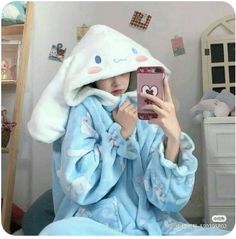 a woman in a blue robe is taking a selfie with her cell phone while wearing an animal - themed bathrobe