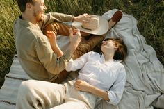 a man and woman laying on a blanket in the grass