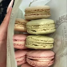 a woman's hand holding a bag full of macaroons