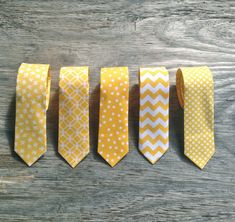 five yellow and white ties lined up on a wooden surface with one knot in the middle