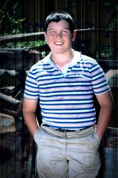 a young man standing in front of an old rusted car with his picture on it