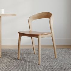 a wooden chair sitting next to a table on top of a carpeted floor in front of a white wall