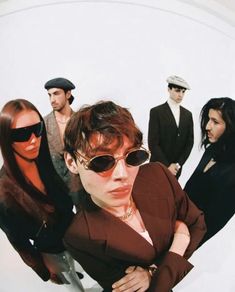 a group of people standing next to each other in front of a white wall with sunglasses on