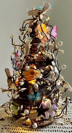 a wire christmas tree decorated with flowers and butterflies