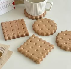 four wooden coasters with holes on them next to a coffee cup and cookie box