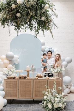 a man and woman standing in front of a table with balloons