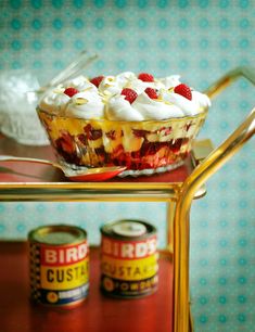 there is a dessert with whipped cream and strawberries in it on the table next to cans