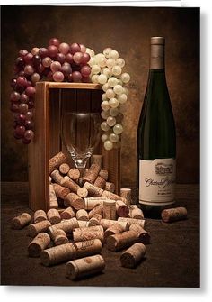 a bottle of wine next to a bunch of grapes and a wooden box filled with corks