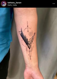 a person's arm with a tattoo on it that has an arrow and mountains