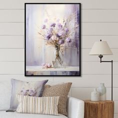 a vase filled with purple flowers sitting on top of a white couch