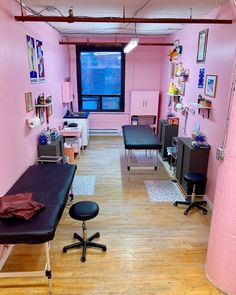 a room with pink walls and black furniture in it, including two desks and chairs