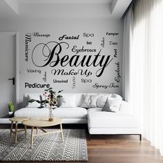 a living room with a white couch and large wall decal that says beauty on it