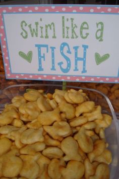 a plastic container filled with nuts next to a sign that says swim like a fish